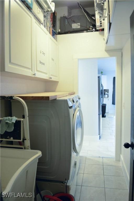 306 Pendleton Ave, Lehigh Acres, FL 33974 - laundry room with washer and clothes dryer, cabinet space, light tile patterned flooring, and baseboards