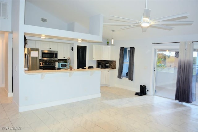 306 Pendleton Ave, Lehigh Acres, FL 33974 - kitchen featuring stainless steel appliances, ceiling fan, white cabinetry, a peninsula, and a kitchen bar