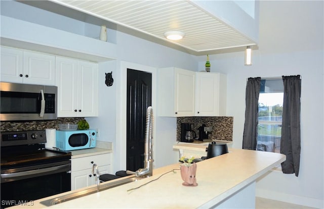 306 Pendleton Ave, Lehigh Acres, FL 33974 - kitchen with stainless steel microwave, range with electric stovetop, white microwave, and backsplash