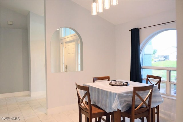 306 Pendleton Ave, Lehigh Acres, FL 33974 - dining area with baseboards, a chandelier, arched walkways, light marble finish flooring, and vaulted ceiling