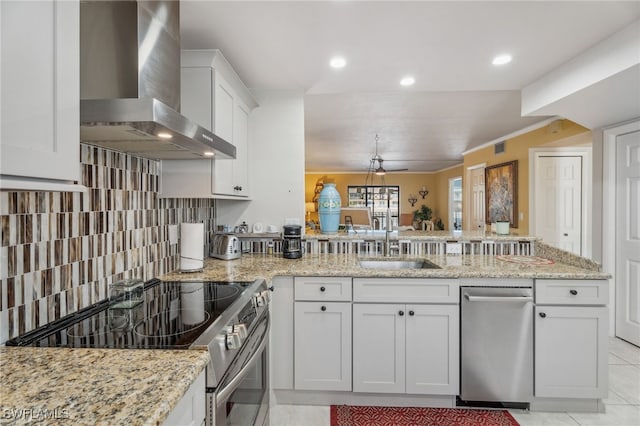 4538 SE 5th Pl Unit 3, Cape Coral, FL 33904 - kitchen featuring wall chimney range hood, stainless steel appliances, a sink, a peninsula, and white cabinets