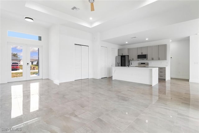 1503 NW 8th Pl, Cape Coral, FL 33993 - unfurnished living room featuring a high ceiling, french doors, light marble finish flooring, recessed lighting, and a tray ceiling