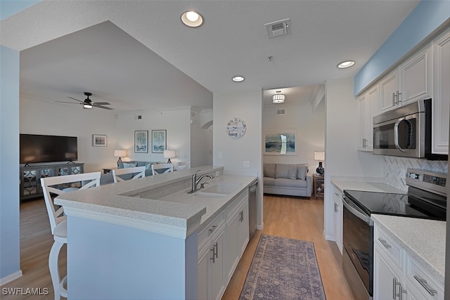 10275 Heritage Bay Blvd Unit 737, Naples, FL 34120 - kitchen with appliances with stainless steel finishes, open floor plan, a sink, light wood-style floors, and a ceiling fan