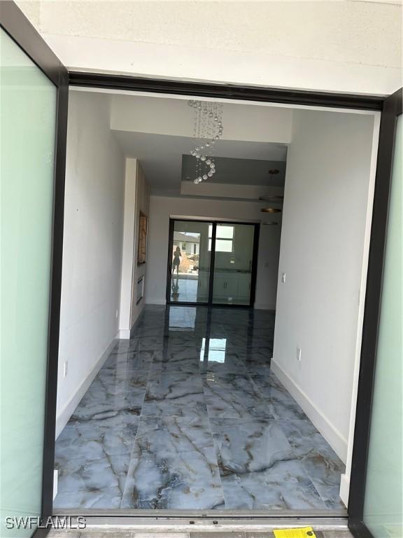 363 SW 24th Ct, Cape Coral, FL 33991 - hallway with marble tiled floors, baseboards, and a chandelier