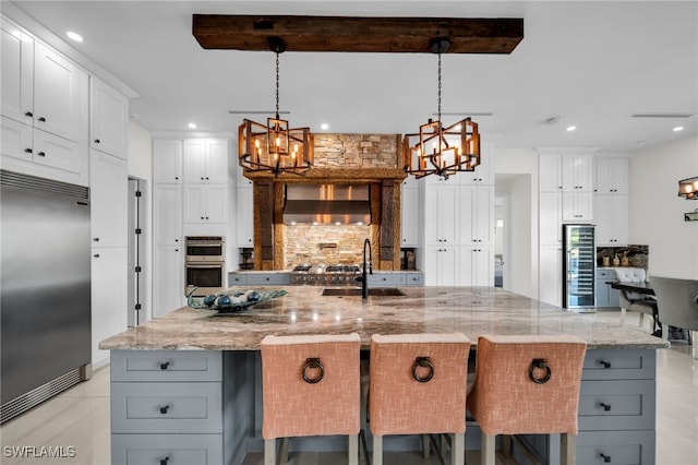 2405 SW 11th Ave, Cape Coral, FL 33991 - kitchen featuring stainless steel appliances, a chandelier, wine cooler, wall chimney exhaust hood, and backsplash