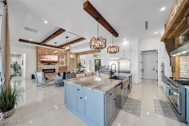 2405 SW 11th Ave, Cape Coral, FL 33991 - kitchen featuring appliances with stainless steel finishes, a fireplace, a chandelier, beam ceiling, and light stone counters