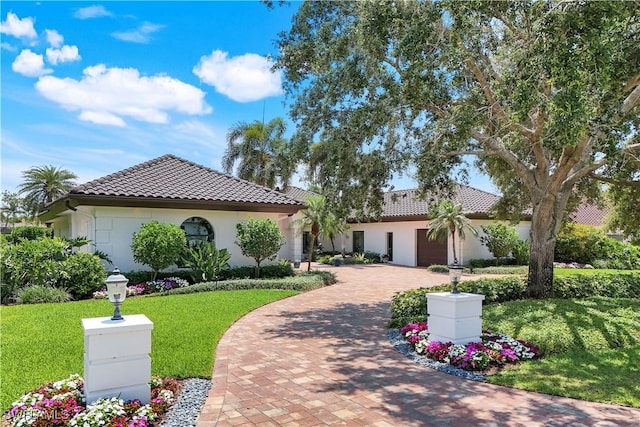 4701 Oak Leaf Dr, Naples, FL 34119 - mediterranean / spanish home with a tiled roof, decorative driveway, stucco siding, and a front yard