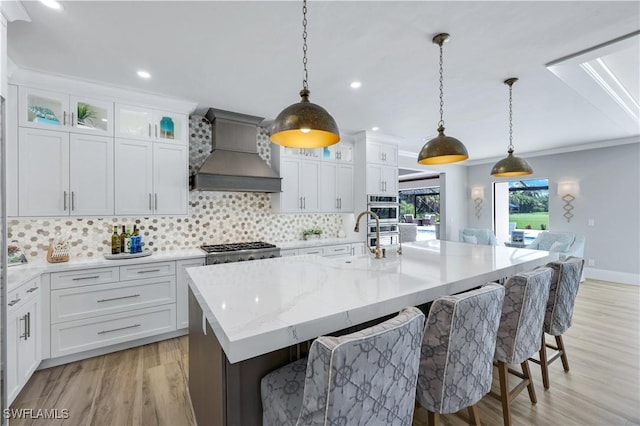 4701 Oak Leaf Dr, Naples, FL 34119 - kitchen featuring custom range hood, a sink, tasteful backsplash, light wood finished floors, and a kitchen bar