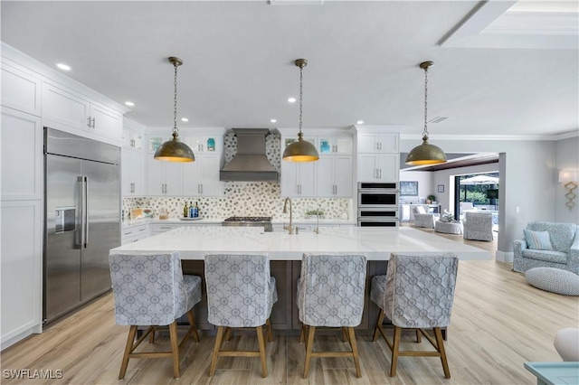 4701 Oak Leaf Dr, Naples, FL 34119 - kitchen featuring stainless steel appliances, premium range hood, decorative backsplash, light wood finished floors, and white cabinets