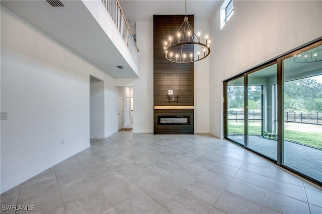 11260 Canopy Loop, Fort Myers, FL 33913 - unfurnished living room with a high ceiling, a chandelier, a glass covered fireplace, light tile patterned floors, and baseboards
