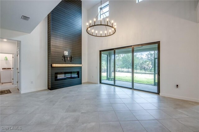 11260 Canopy Loop, Fort Myers, FL 33913 - unfurnished living room with a high ceiling, washer / clothes dryer, a large fireplace, tile patterned floors, and a chandelier