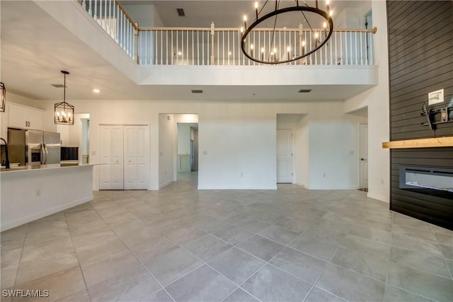 11260 Canopy Loop, Fort Myers, FL 33913 - unfurnished living room with a high ceiling, a chandelier, a large fireplace, light tile patterned floors, and baseboards