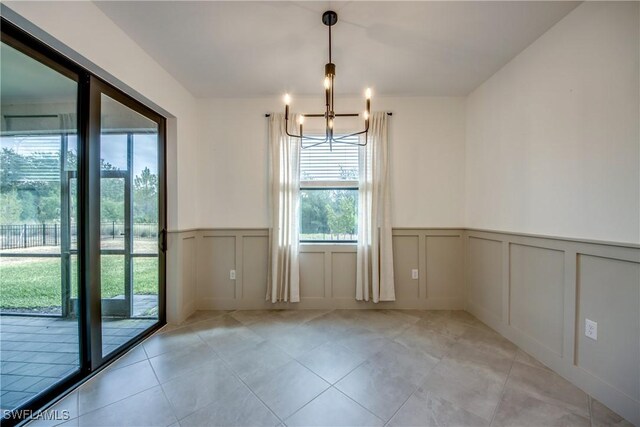 11260 Canopy Loop, Fort Myers, FL 33913 - unfurnished dining area with a decorative wall, a chandelier, a wainscoted wall, and light tile patterned flooring