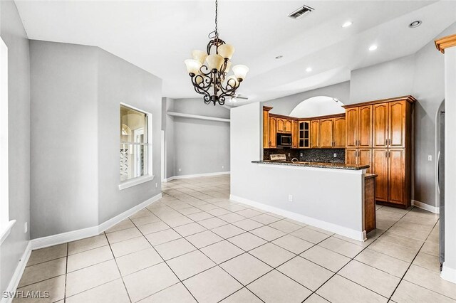 707 8th Ave, Lehigh Acres, FL 33972 - kitchen featuring stainless steel microwave, a chandelier, glass insert cabinets, brown cabinetry, and decorative backsplash