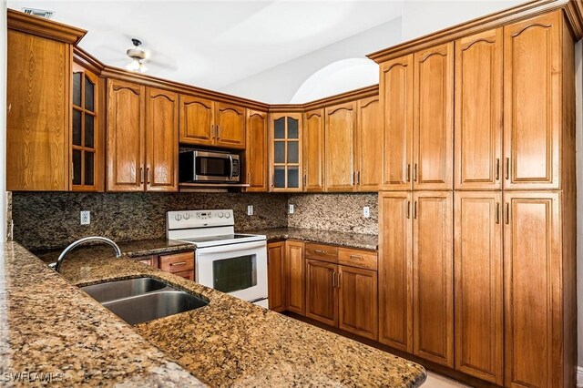 707 8th Ave, Lehigh Acres, FL 33972 - kitchen featuring white electric range, stainless steel microwave, a sink, stone counters, and brown cabinetry