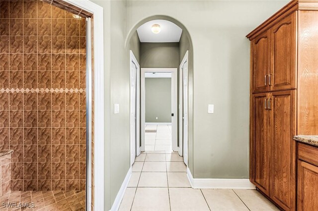 707 8th Ave, Lehigh Acres, FL 33972 - hallway with light tile patterned flooring, arched walkways, and baseboards
