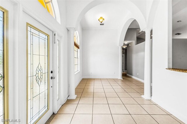 707 8th Ave, Lehigh Acres, FL 33972 - foyer featuring arched walkways, decorative columns, light tile patterned flooring, and baseboards