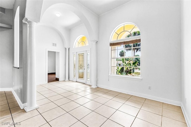 707 8th Ave, Lehigh Acres, FL 33972 - foyer entrance featuring plenty of natural light, decorative columns, light tile patterned floors, a high ceiling, and baseboards