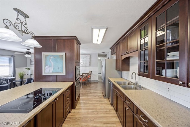 736 94th Ave N, Naples, FL 34108 - kitchen with a sink, appliances with stainless steel finishes, light wood finished floors, hanging light fixtures, and decorative backsplash