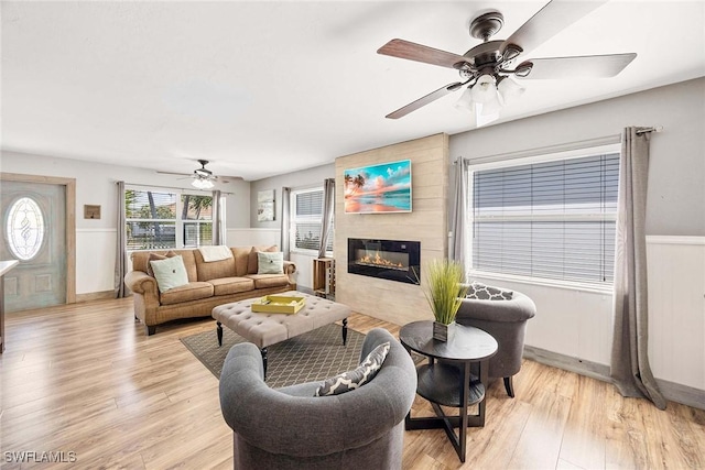 736 94th Ave N, Naples, FL 34108 - living area with a ceiling fan, light wood-type flooring, a large fireplace, and a wainscoted wall