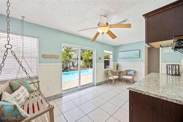 736 94th Ave N, Naples, FL 34108 - dining room featuring wainscoting, a textured ceiling, ceiling fan, and light tile patterned floors