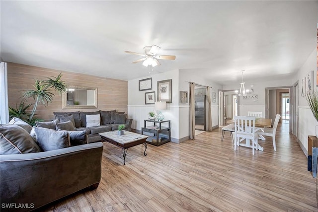 668 94th Ave N, Naples, FL 34108 - living area featuring a chandelier, light wood-type flooring, ceiling fan, a wainscoted wall, and wood walls