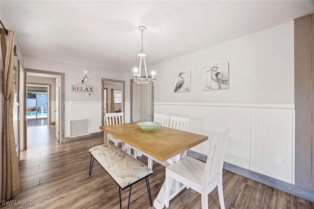 668 94th Ave N, Naples, FL 34108 - dining space with a chandelier, a wainscoted wall, wood finished floors, and plenty of natural light