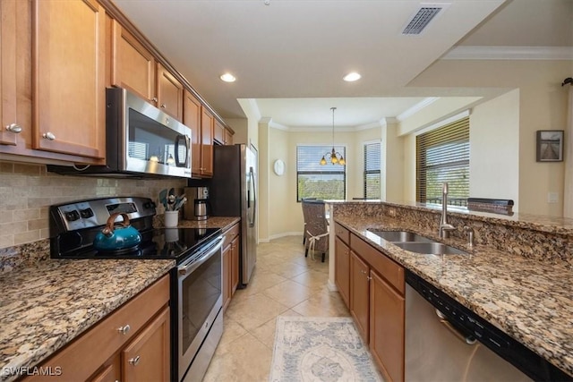 9731 Acqua Ct Unit 537, Naples, FL 34113 - kitchen featuring appliances with stainless steel finishes, a sink, brown cabinetry, tasteful backsplash, and stone counters