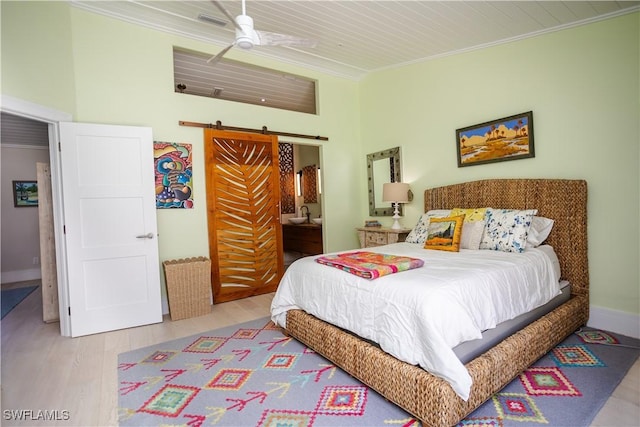5880 Shady Oaks Ln, Naples, FL 34119 - bedroom with a barn door, wood finished floors, ornamental molding, ensuite bath, and a ceiling fan