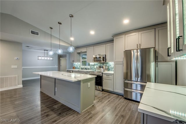 14160 Cedardale St, Fort Myers, FL 33905 - kitchen with stainless steel appliances, a kitchen island, wood finished floors, pendant lighting, and tasteful backsplash