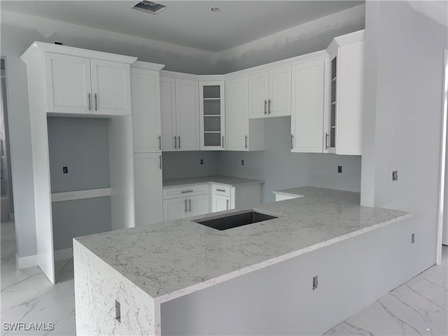 3346 10th Ave SE, Naples, FL 34117 - kitchen with light marble finish floors, light stone counters, glass insert cabinets, white cabinets, and a peninsula