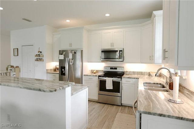 12083 Maiden Ln, Bonita Springs, FL 34135 - kitchen with appliances with stainless steel finishes, a sink, white cabinets, light stone counters, and light wood-style floors
