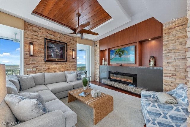 13675 Vanderbilt Dr Ph 1105, Naples, FL 34110 - living room featuring a ceiling fan, a tray ceiling, a glass covered fireplace, wooden ceiling, and wood finished floors