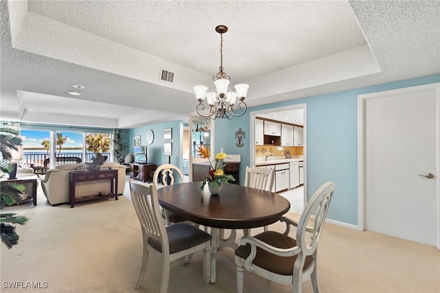 1036 S Collier Blvd Unit A103, Marco Island, FL 34145 - dining room with light colored carpet, a chandelier, a textured ceiling, and a raised ceiling