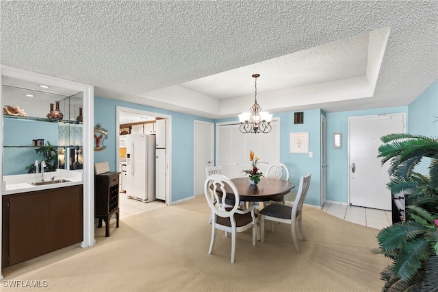 1036 S Collier Blvd Unit A103, Marco Island, FL 34145 - dining area with light tile patterned floors, a textured ceiling, a chandelier, a tray ceiling, and light carpet