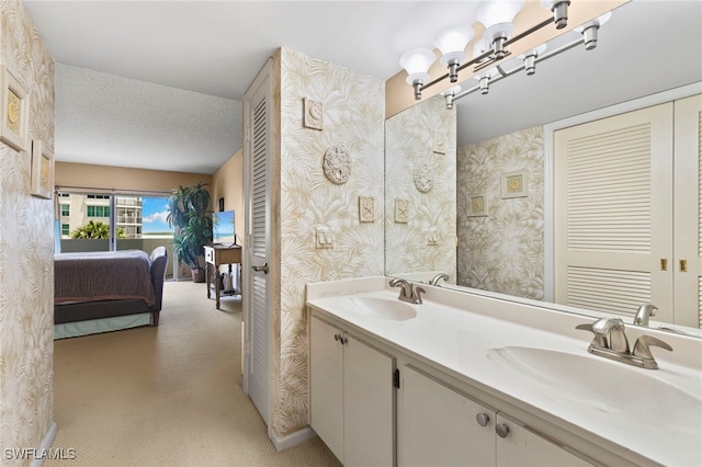 1036 S Collier Blvd Unit A103, Marco Island, FL 34145 - bathroom featuring double vanity, wallpapered walls, a textured ceiling, and ensuite bath