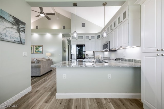 910 Gen George Patton Ave, Labelle, FL 33935 - kitchen featuring stainless steel microwave, a peninsula, light wood-type flooring, light stone counters, and white cabinets