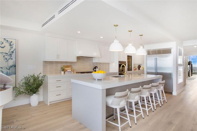 13945 Old Coast Rd Unit 2204, Naples, FL 34110 - kitchen with appliances with stainless steel finishes, light wood-style floors, decorative backsplash, custom exhaust hood, and recessed lighting