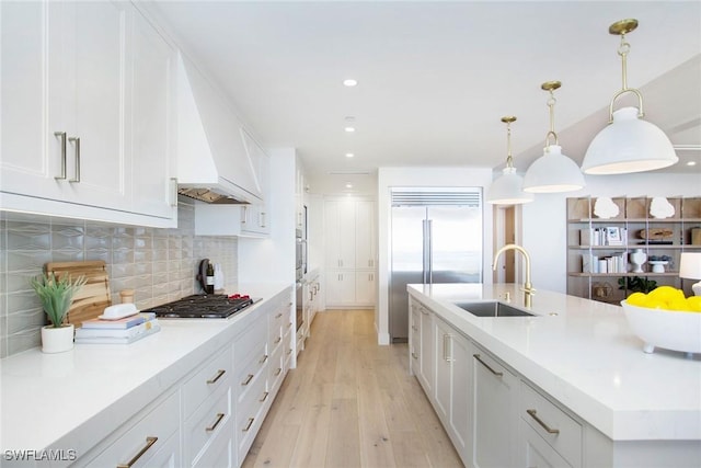 13945 Old Coast Rd Unit 2204, Naples, FL 34110 - kitchen with appliances with stainless steel finishes, tasteful backsplash, white cabinetry, light wood-type flooring, and light countertops