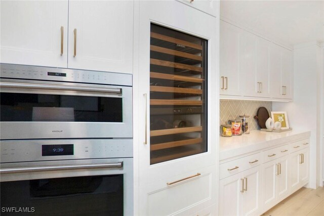 13945 Old Coast Rd Unit 2204, Naples, FL 34110 - kitchen featuring double oven, white cabinets, tasteful backsplash, and light countertops