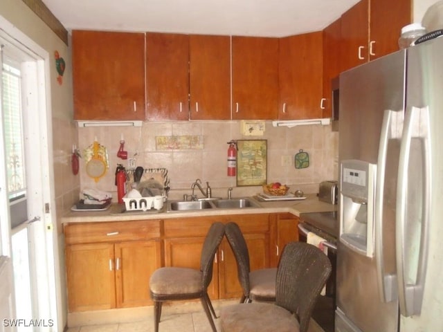2956 Powell St, Fort Myers, FL 33901 - kitchen featuring stainless steel fridge with ice dispenser, a sink, backsplash, light countertops, and brown cabinets