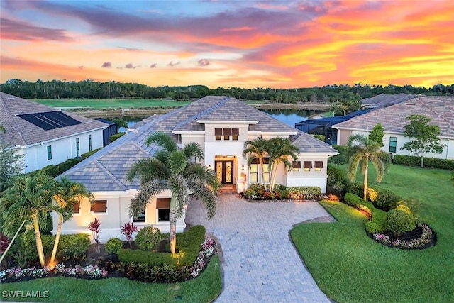 9010 Arrezo Ct, Naples, FL 34119 - view of front facade featuring stucco siding, french doors, decorative driveway, and a water view