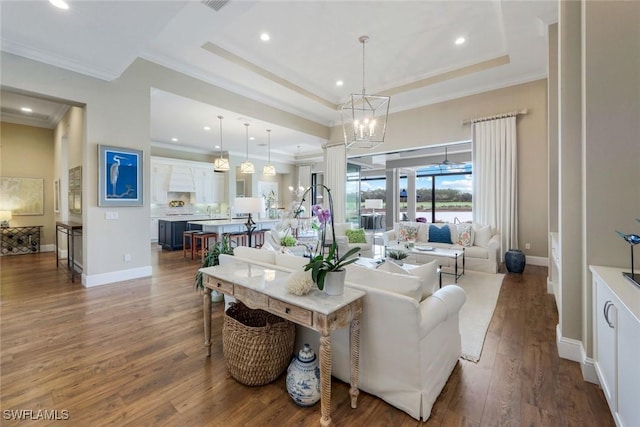 9010 Arrezo Ct, Naples, FL 34119 - living room with ornamental molding, wood finished floors, recessed lighting, a chandelier, and a raised ceiling
