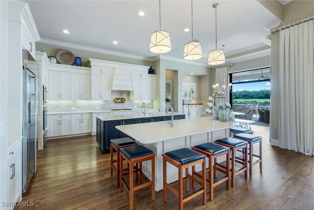 9010 Arrezo Ct, Naples, FL 34119 - kitchen featuring an island with sink, custom exhaust hood, ornamental molding, white stovetop, and a kitchen bar