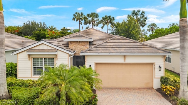 14687 Topsail Dr, Naples, FL 34114 - view of front of house featuring a garage, decorative driveway, a chimney, and a tiled roof