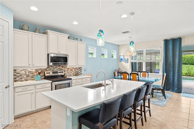 14687 Topsail Dr, Naples, FL 34114 - kitchen featuring stainless steel appliances, a sink, decorative backsplash, light countertops, and a breakfast bar area