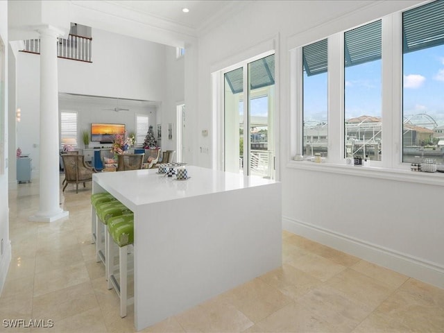 434 Conners Ave, Naples, FL 34108 - kitchen featuring ornate columns, crown molding, a center island, light tile patterned floors, and a towering ceiling