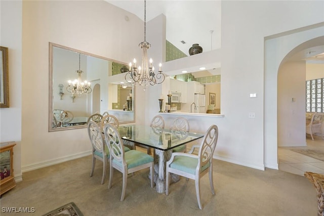 795 Bentwater Cir Unit 202, Naples, FL 34108 - dining area featuring a chandelier, arched walkways, carpet floors, high vaulted ceiling, and baseboards
