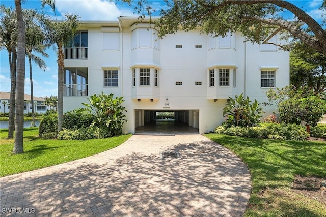 795 Bentwater Cir Unit 202, Naples, FL 34108 - view of building exterior featuring a carport, decorative driveway, and a water view