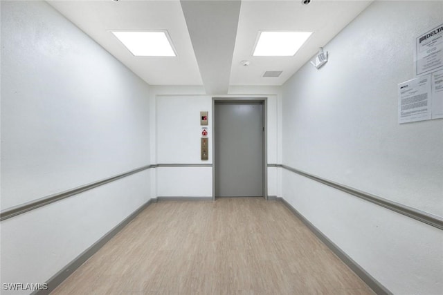 795 Bentwater Cir Unit 202, Naples, FL 34108 - empty room with elevator, light wood-style floors, and baseboards